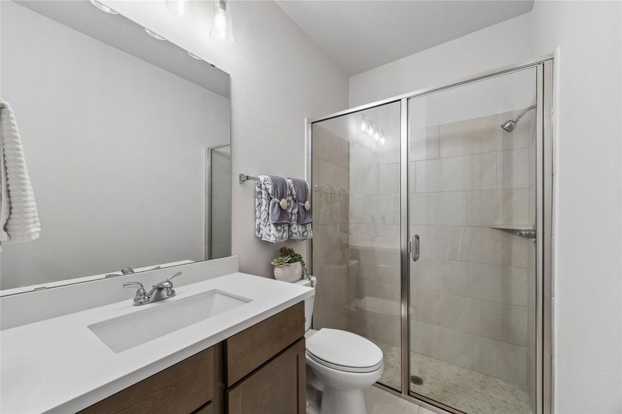 Full first-floor guest bath featuring a quartz vanity and walk-in glass enclosed shower