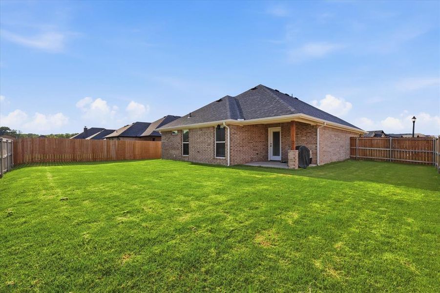 Fenced grassy backyard offering plenty of space for outdoor activities, pets, and entertaining.