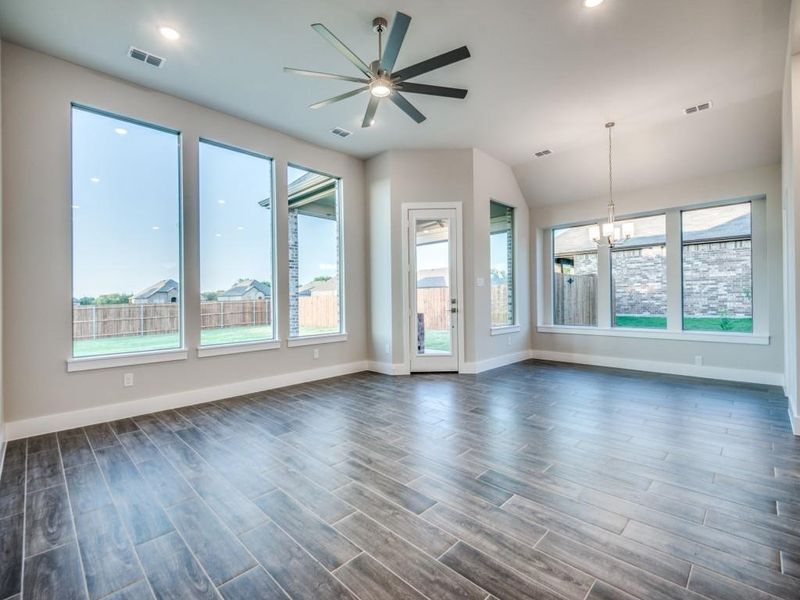Unfurnished living room with plenty of natural light, ceiling fan with notable chandelier, and visible vents Unfurnished living room with plenty of natural light, ceiling fan with notable chandelier, and visible vents