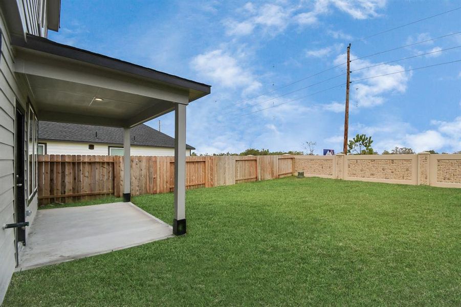 Another perspective of the covered patio an extensive backyard.