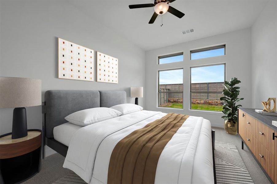 This room features a vaulted ceiling, a ceiling fan with integrated lighting, and large windows providing views of the exterior green space