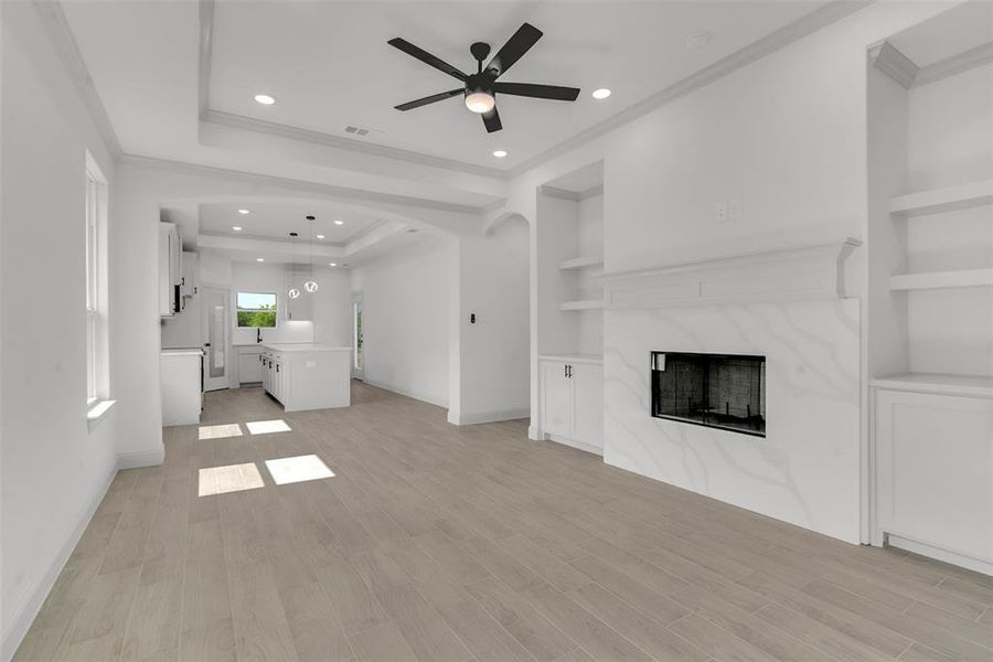 Unfurnished living room with a ceiling fan, crown molding, a premium fireplace, built in features, and recessed lighting Unfurnished living room with a ceiling fan, crown molding, a premium fireplace, built in features, and recessed lighting