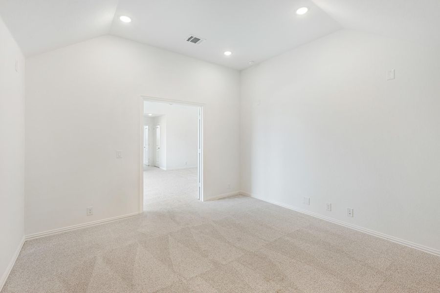 Empty bedroom with vaulted ceiling, recessed lighting, and beige carpet flooring Empty bedroom with vaulted ceiling, recessed lighting, and beige carpet flooring