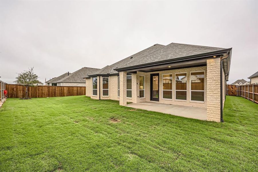 Rear view of property featuring a lawn and a patio