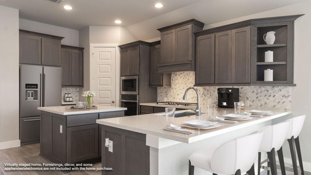 Kitchen with stainless steel appliances, a peninsula, light countertops, dark brown cabinetry, and backsplash