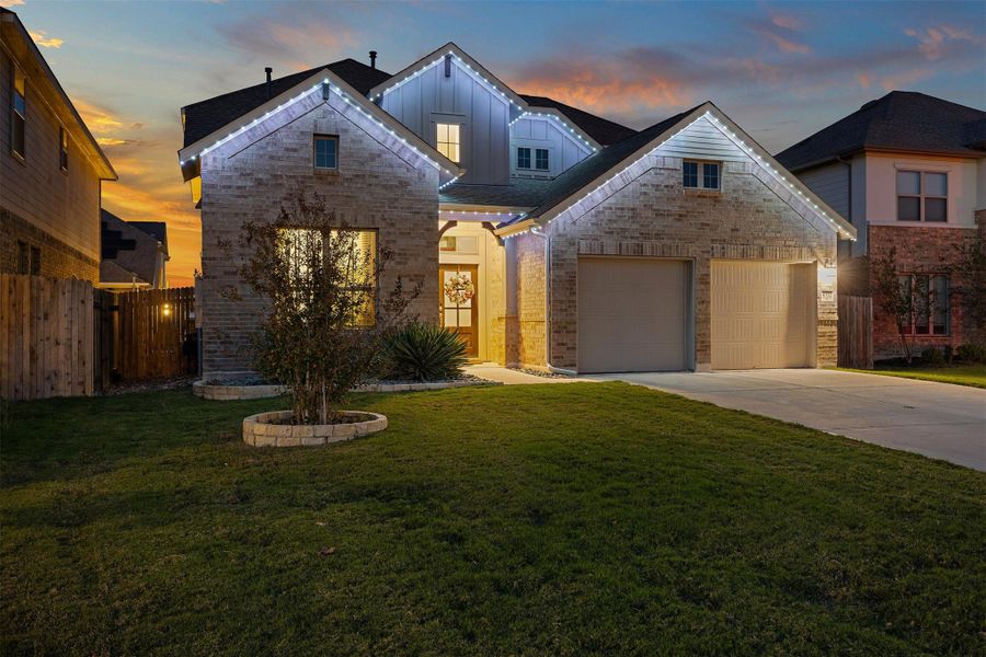 The front of the home offers a welcoming first impression with permanent outdoor lighting that adds a soft evening glow