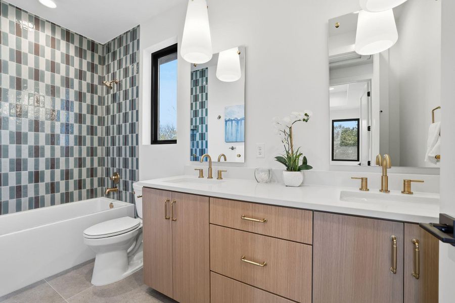 Bathroom featuring double vanity, bathtub / shower combination, and light tile patterned flooring