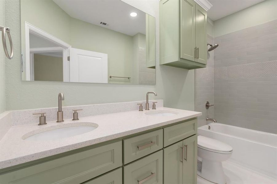 Full bathroom featuring double sink vanity, toilet, and tiled shower / bath