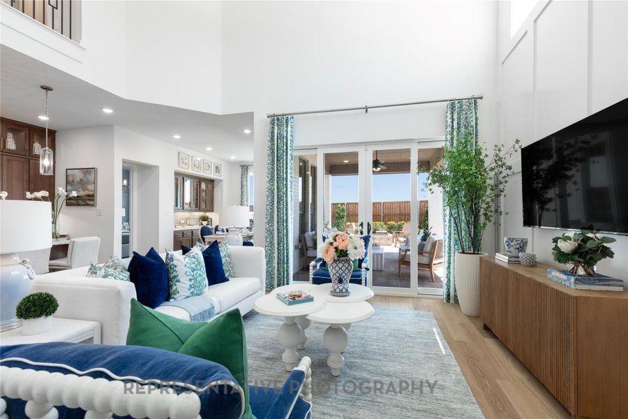 Living room with light wood-type flooring, a towering ceiling, and french doors