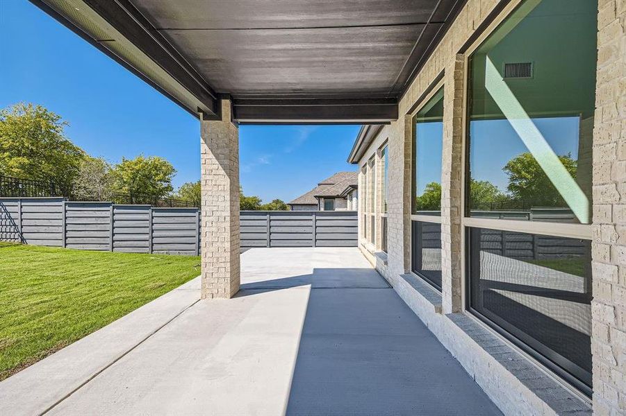 Expansive covered patio featuring a concrete surface and a light brick column Expansive covered patio featuring a concrete surface and a light brick column