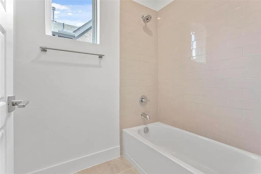 Bathroom featuring tile patterned flooring and tiled shower / bath combo