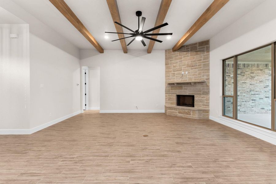 Unfurnished living room featuring a fireplace, beam ceiling, light wood finished floors, and a ceiling fan Unfurnished living room featuring a fireplace, beam ceiling, light wood finished floors, and a ceiling fan