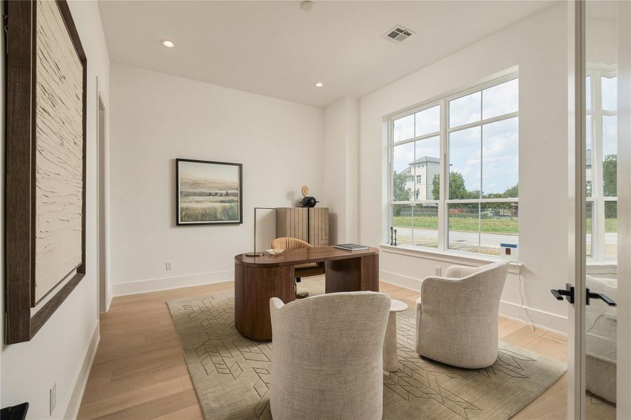 A dedicated home office is filled with natural light, offering a polished and private setting for work, meetings, or quiet focus.