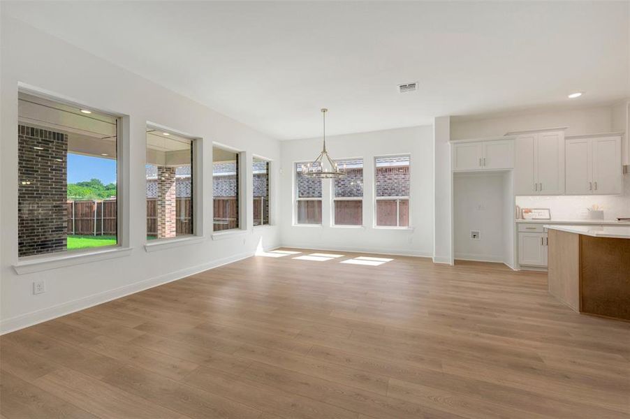 Open-concept living space featuring wood-finish flooring, white walls, and multiple windows Open-concept living space featuring wood-finish flooring, white walls, and multiple windows