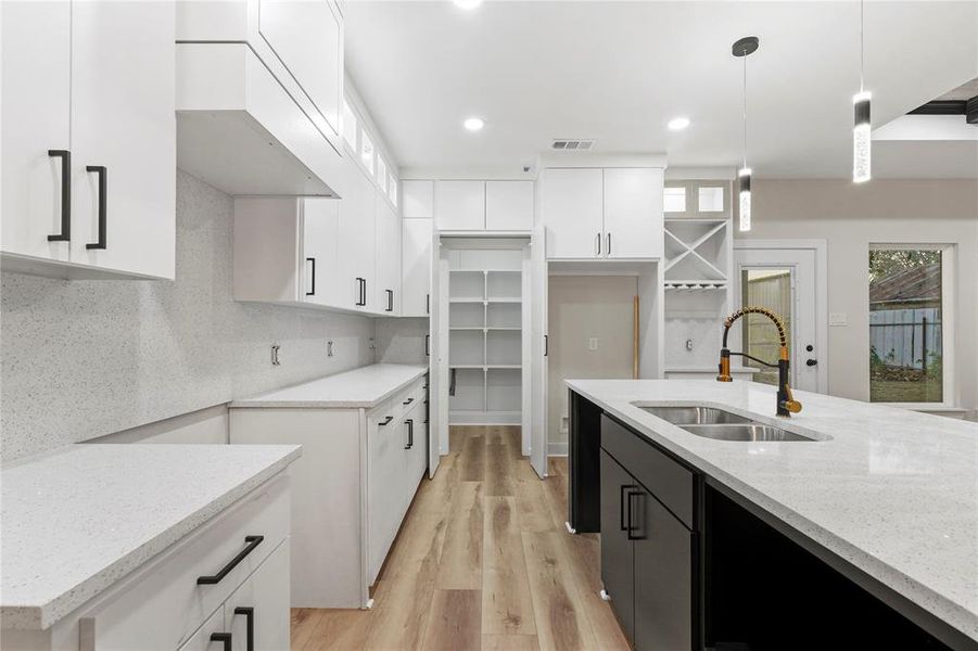 Kitchen featuring white cabinets, light stone counters, light wood finished floors, hanging light fixtures, and recessed lighting Kitchen featuring white cabinets, light stone counters, light wood finished floors, hanging light fixtures, and recessed lighting