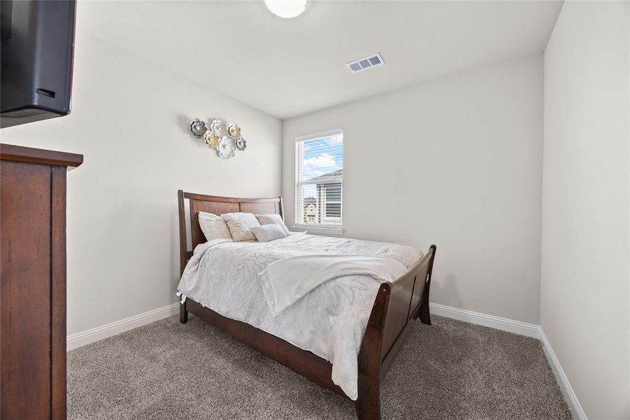 This well-appointed secondary bedroom is one of three comfortable bedrooms located on the second level. Featuring neutral walls, plush carpeting, and a bright window that fills the space with natural light, it offers the perfect layout for a growing family, a cozy guest room, or a dedicated home office.