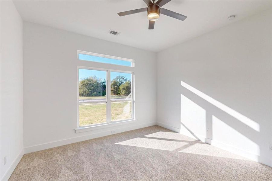 Carpeted empty room featuring ceiling fan, baseboards, and visible vents
