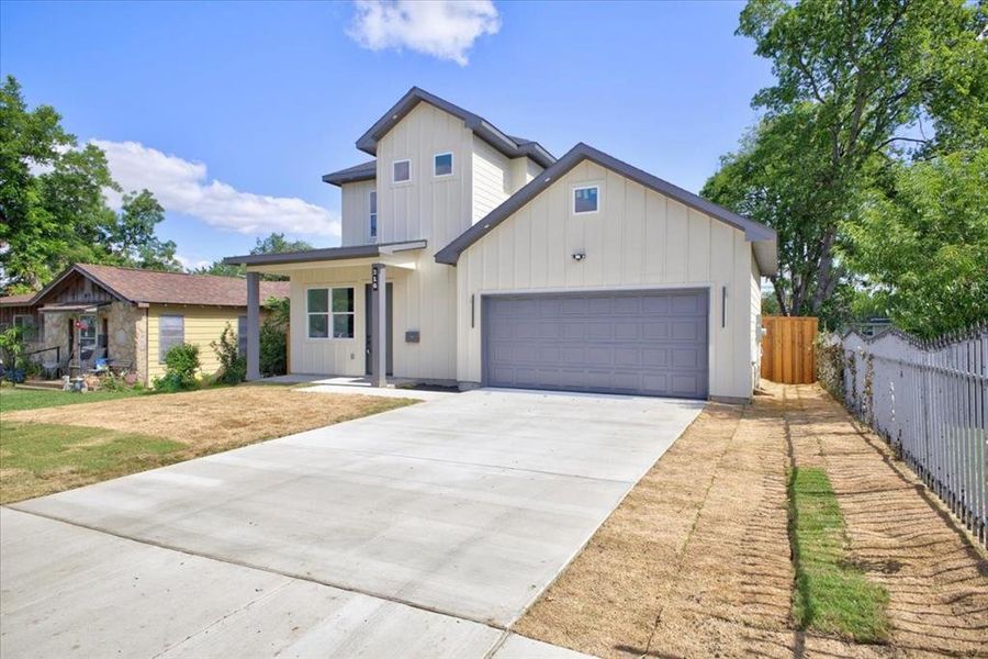 Modern architectural design featuring vertical siding, a two-car garage, a covered entry, dark trim accents, and a concrete driveway Modern architectural design featuring vertical siding, a two-car garage, a covered entry, dark trim accents, and a concrete driveway