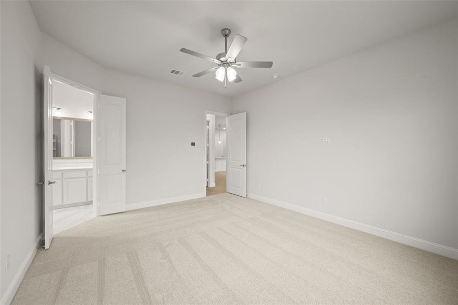 Unfurnished bedroom with light carpet, connected bathroom, and a ceiling fan