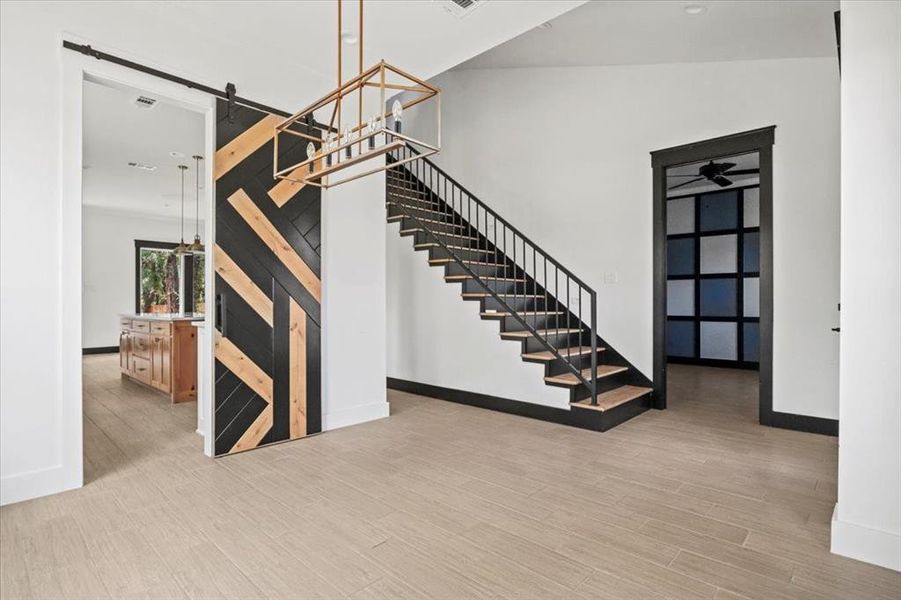 Stairway with a barn door and wood finished floors