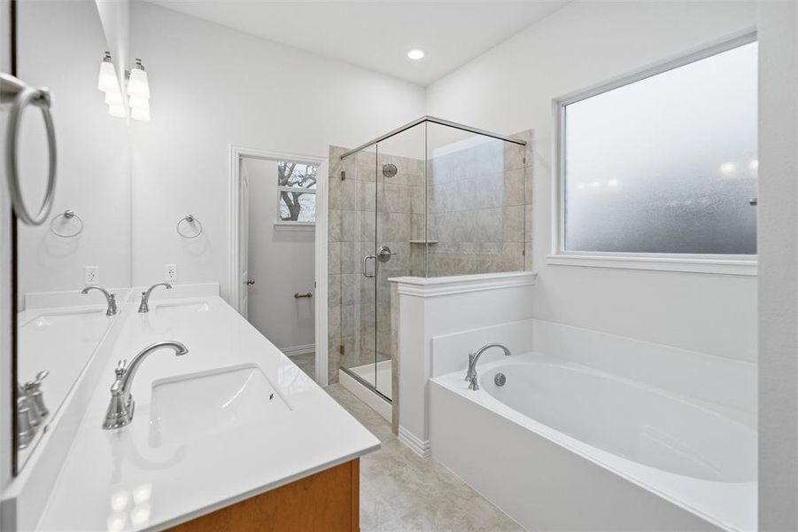 Full bath featuring a garden tub, double vanity, and a shower stall Full bath featuring a garden tub, double vanity, and a shower stall