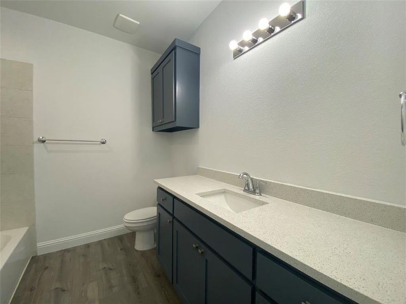 Full bathroom featuring dark wood-style floors, vanity, and shower / bathtub combination Full bathroom featuring dark wood-style floors, vanity, and shower / bathtub combination