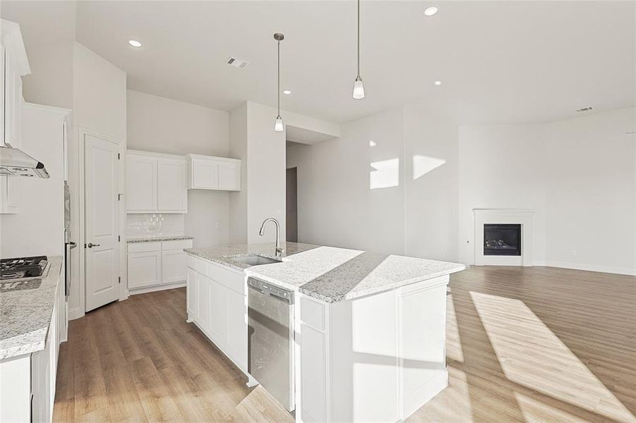 Kitchen featuring white cabinetry, dishwasher, sink, and a center island with sink