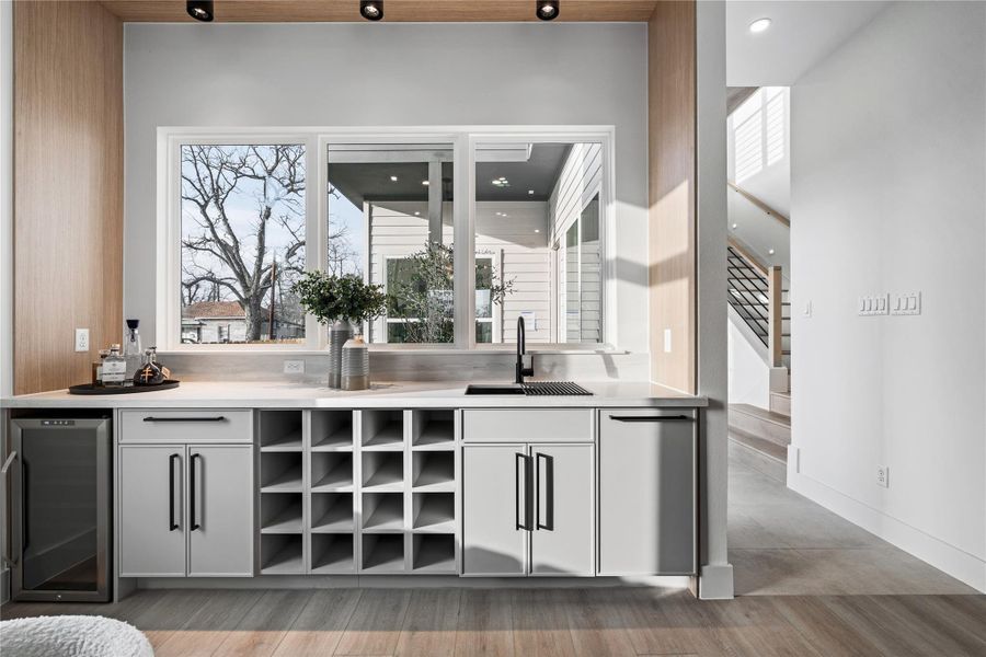A dedicated wet bar overlooks the private outdoor space, framed like a living piece of art. It’s a seamless extension of the home’s entertaining flow.