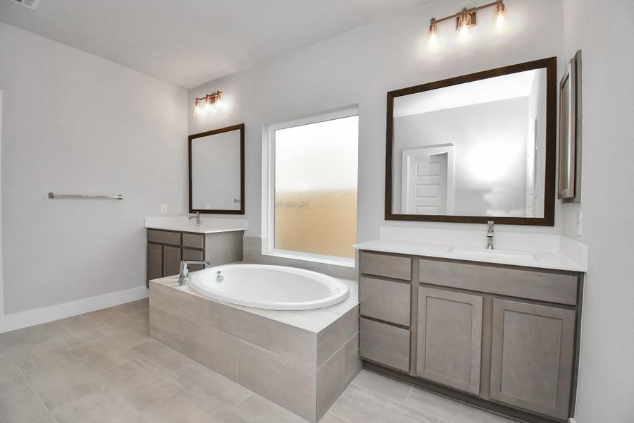 Indulge in a spa-like retreat within the confines of this primary bathroom. Delight in a spacious walk-in shower enveloped in stylish tile surround and unwind in a separate garden tub adorned with custom detailing. Sample photo of completed home with similar floor plan. Actual colors and selections may vary. Indulge in a spa-like retreat within the confines of this primary bathroom. Delight in a spacious walk-in shower enveloped in stylish tile surround and unwind in a separate garden tub adorned with custom detailing. Sample photo of completed home with similar floor plan. Actual colors and selections may vary.