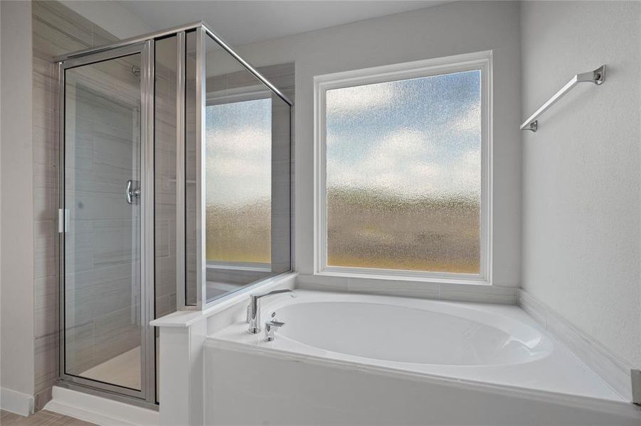 Wow! Look at this primary bathroom! Featuring dark framed walk-in shower with tile surround, separate garden tub for soaking after a long day.