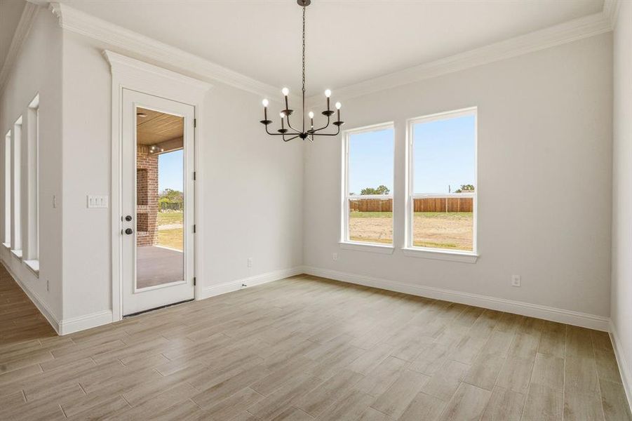 Unfurnished dining area featuring a chandelier, light wood finished floors, and ornamental molding