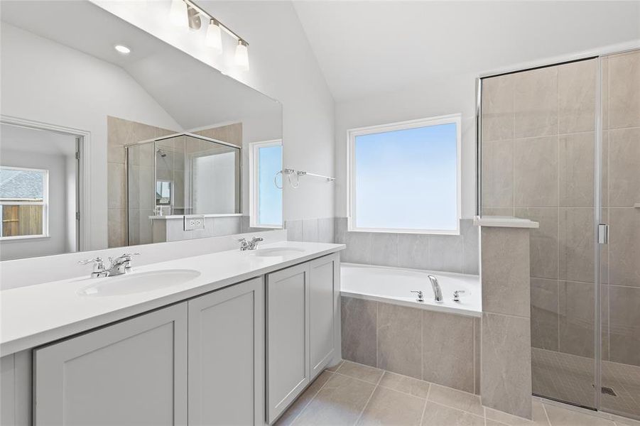 Bathroom with a stall shower, double vanity, vaulted ceiling, a garden tub, and light tile patterned floors