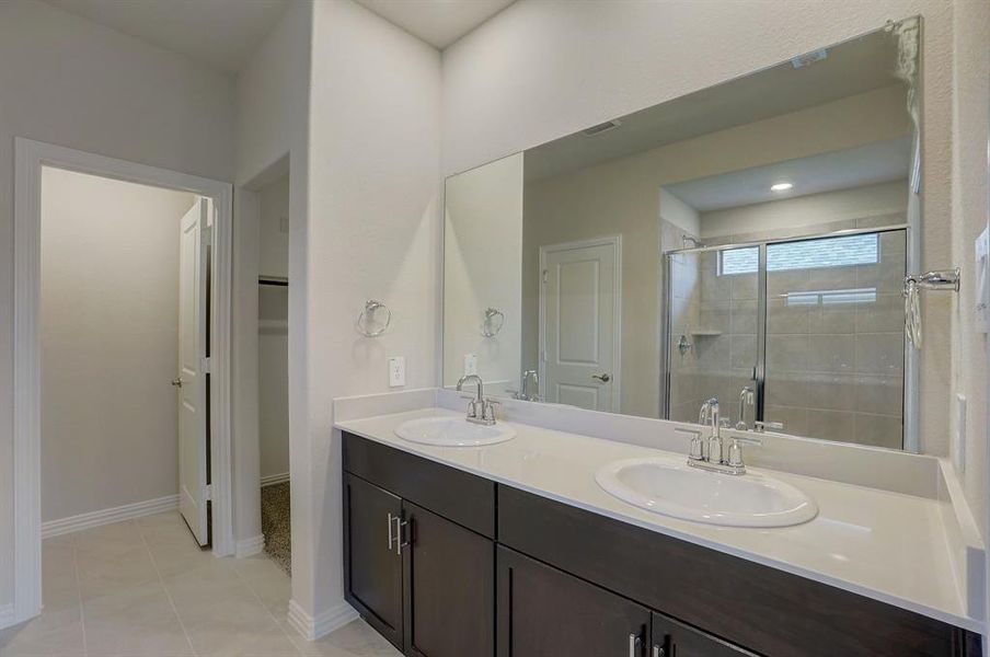 Bathroom with dual vanity, tile patterned flooring, and an enclosed shower