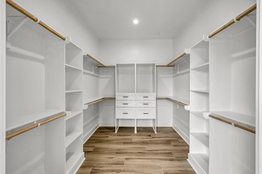 Large custom walk-in closet with built-in shelving, hanging space, and drawer storage designed for maximum organization and convenience.