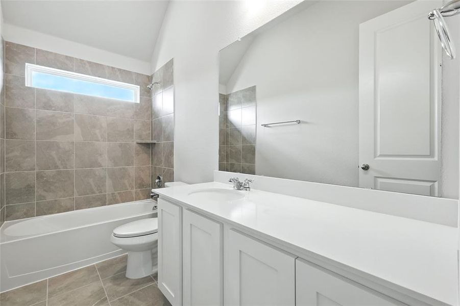 Full bath with vanity, bathing tub / shower combination, light tile patterned floors, and lofted ceiling Full bath with vanity, bathing tub / shower combination, light tile patterned floors, and lofted ceiling