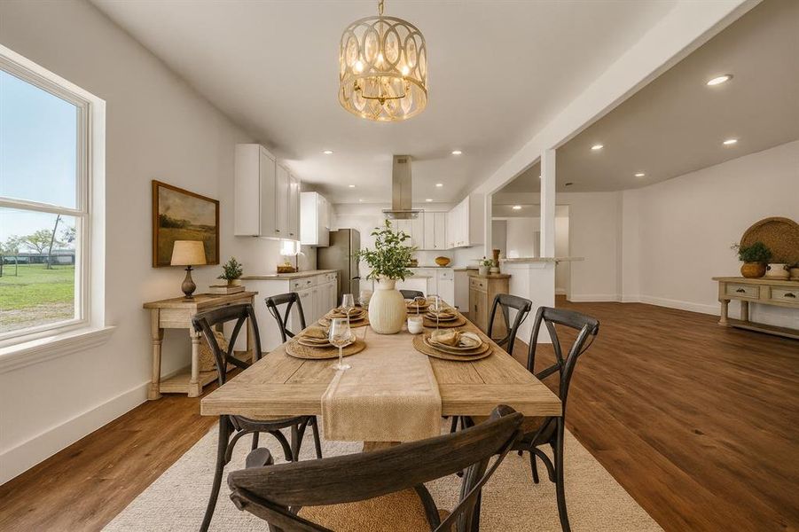 Staged - Dining room with dark wood finished floors, a chandelier, and recessed lighting