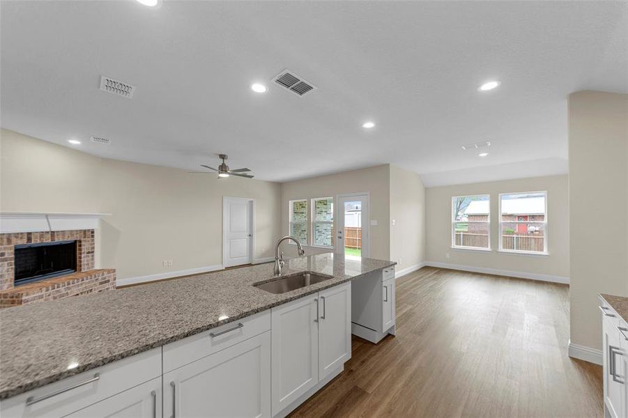 Kitchen island with granite countertops, stainless steel sink, and white cabinetry