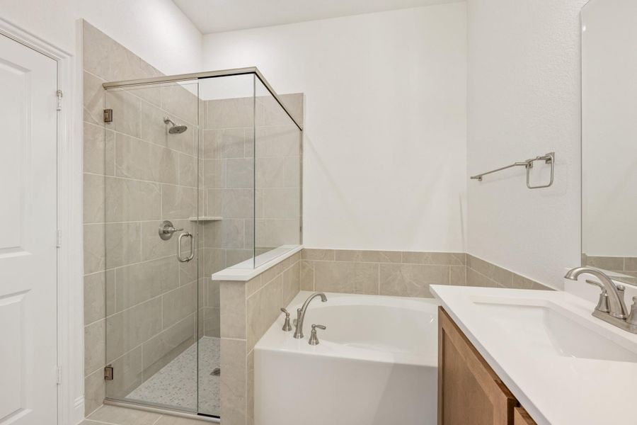 Bathroom with glass-enclosed shower, soaking tub, and wood vanity with white countertop