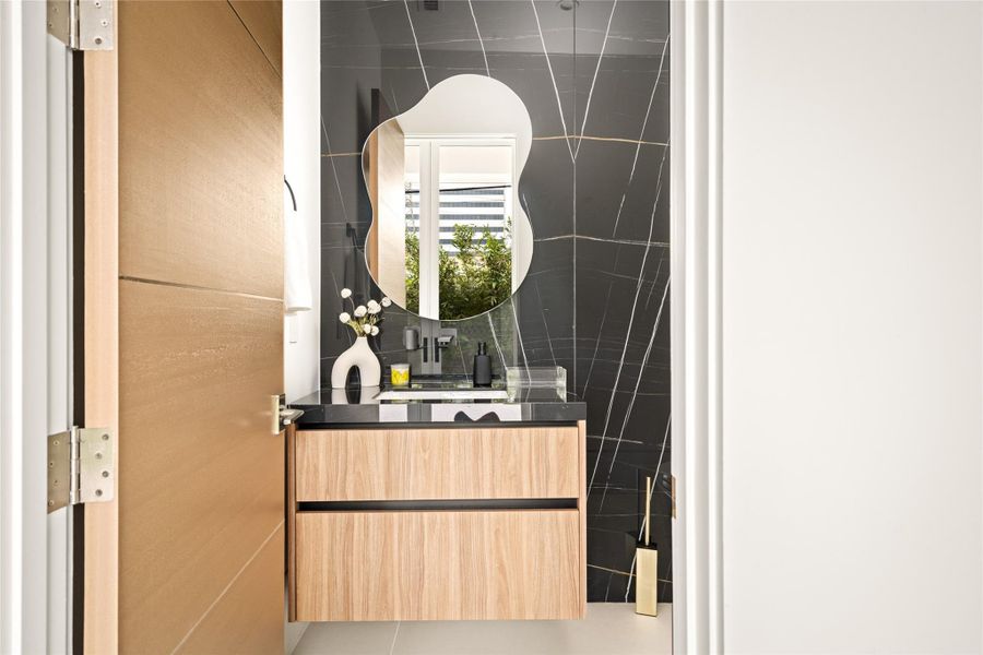 Striking powder bath featuring dramatic stone walls, a floating vanity, and sculptural mirror.