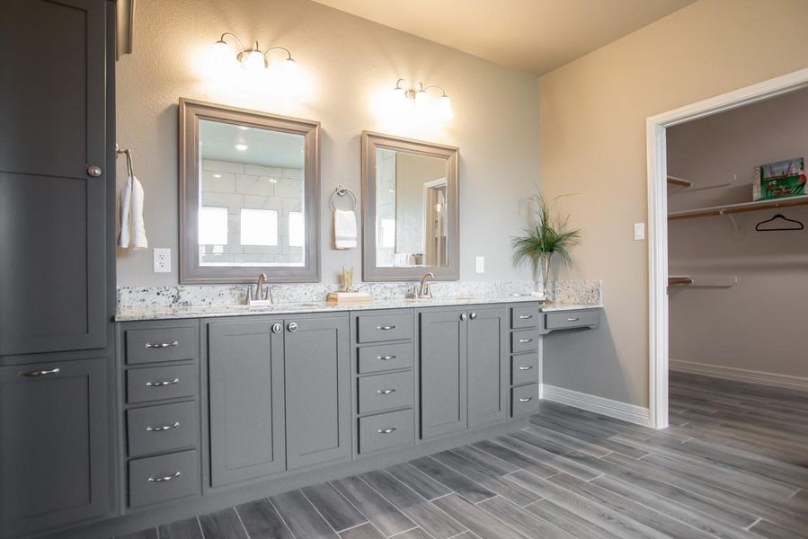Full bath with double vanity, wood finished floors, and a spacious closet Full bath with double vanity, wood finished floors, and a spacious closet