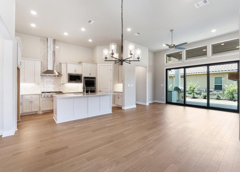 Kitchen featuring open floor plan, ceiling fan, light countertops, white cabinets, and light wood finished floors