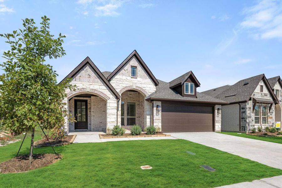 Single-story home with stone exterior, arched entry, two-car garage, and green front lawn