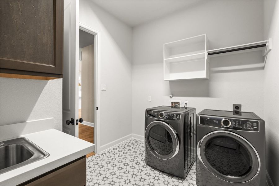 Modern laundry room featuring sleek appliances, patterned tile flooring, and ample storage with cabinets and shelving.