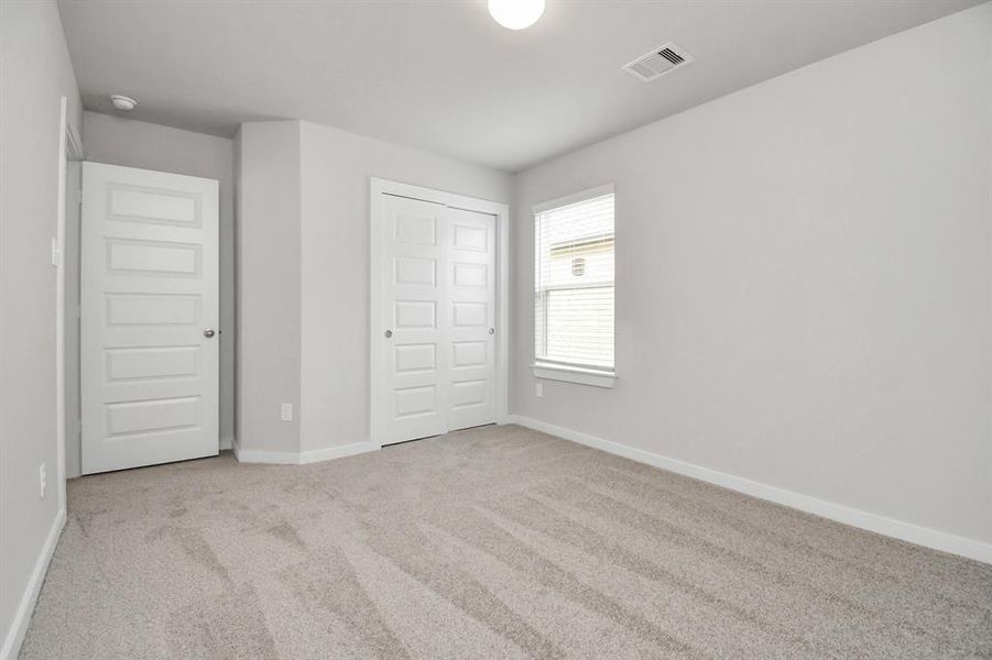 Secondary bedroom features plush carpeting, large windows that let in plenty of natural light, bright paint, and spacious closets.