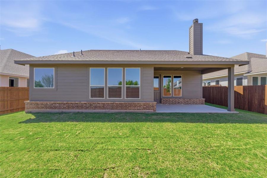 Back of property featuring a fenced backyard, a patio area, brick siding, a chimney, and a shingled roof