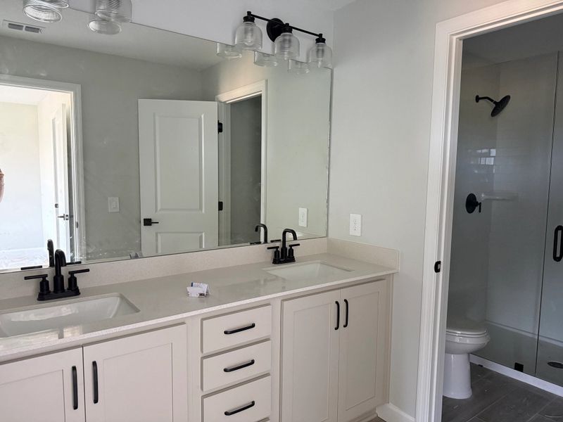 Luxurious primary bathroom with frameless glass shower, featuring the AW Artisan Collection