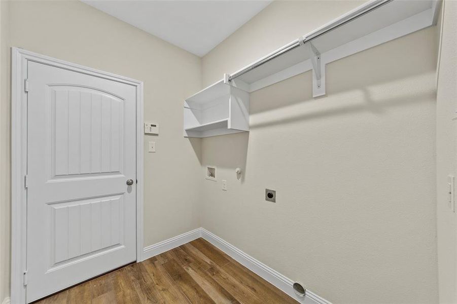 Clothes washing area with gas dryer hookup, washer hookup, hardwood / wood-style flooring, and hookup for an electric dryer