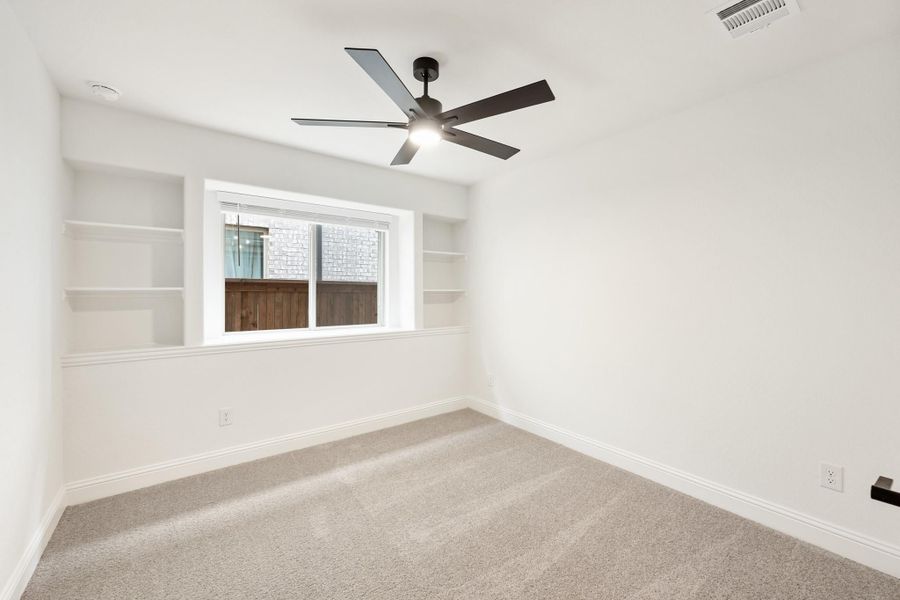 Empty bedroom with carpet, ceiling fan, built-in shelves flanking a window, and white walls Empty bedroom with carpet, ceiling fan, built-in shelves flanking a window, and white walls