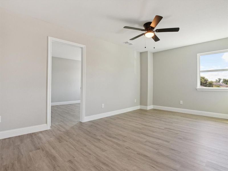 Empty room with ceiling fan and light hardwood / wood-style floors