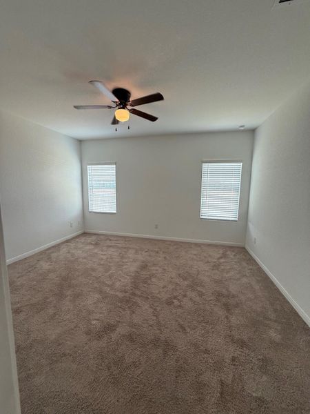 A spacious bedroom offers comfort with soft carpeting and ample natural light from twin windows.